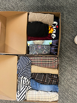 Two shoeboxes filled with a variety of folded clothing.