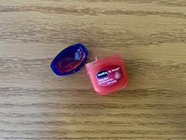 An open jar of pink-tinted Vaseline Lip Therapy